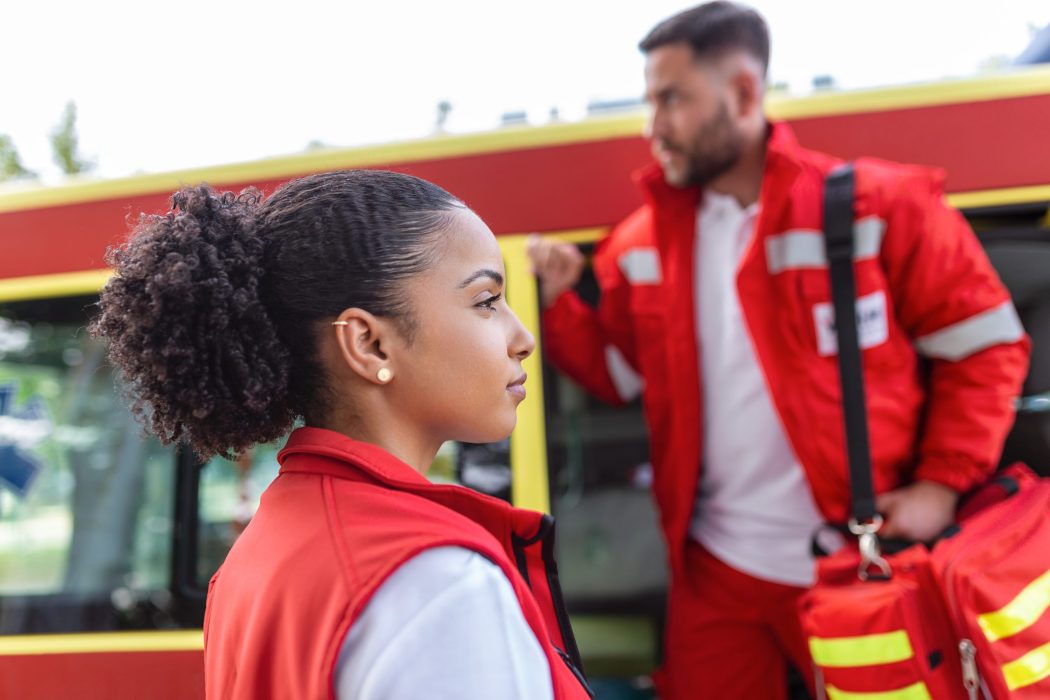 Paramedic nurse and emergency doctor at ambulance with kit. a paramedic, standing at the rear of an ambulance, by the open doors.